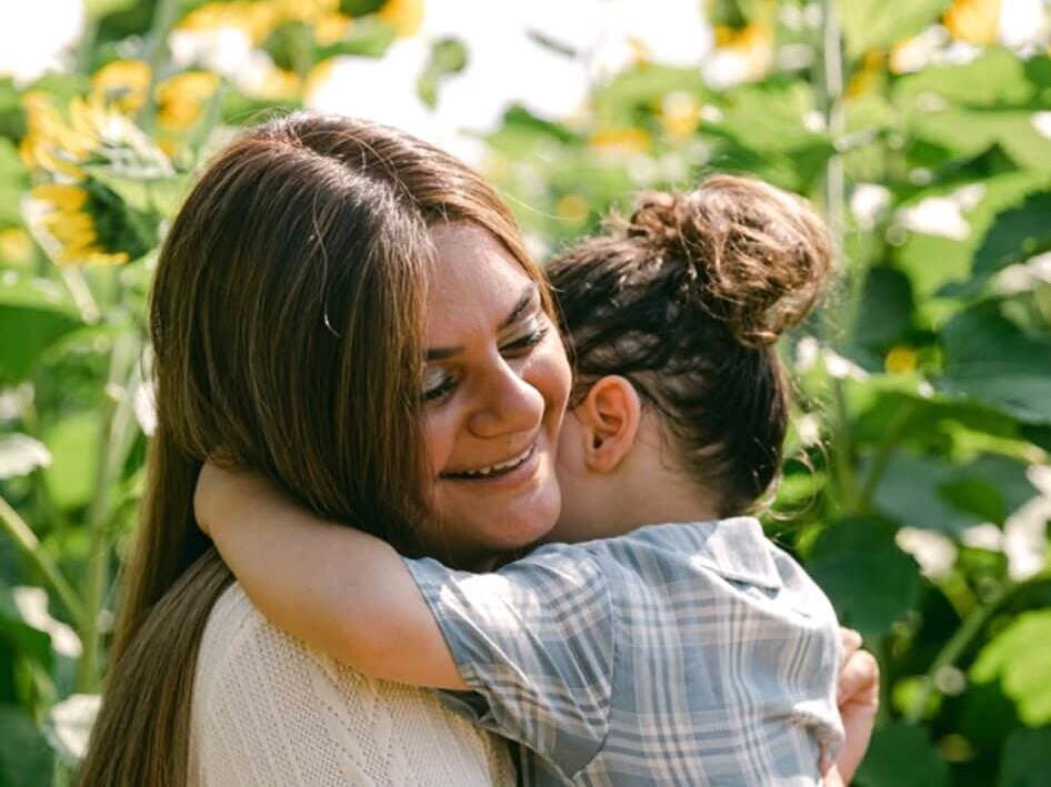 A client hugging her young son in a sunflower field