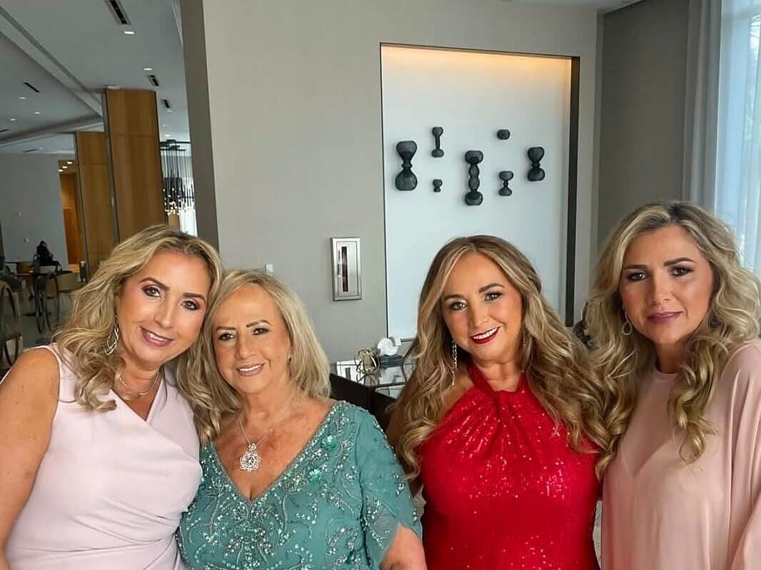 Four women dressed for a family celebration, smiling together